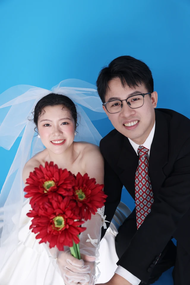 两位新人手捧红花向镜头微笑